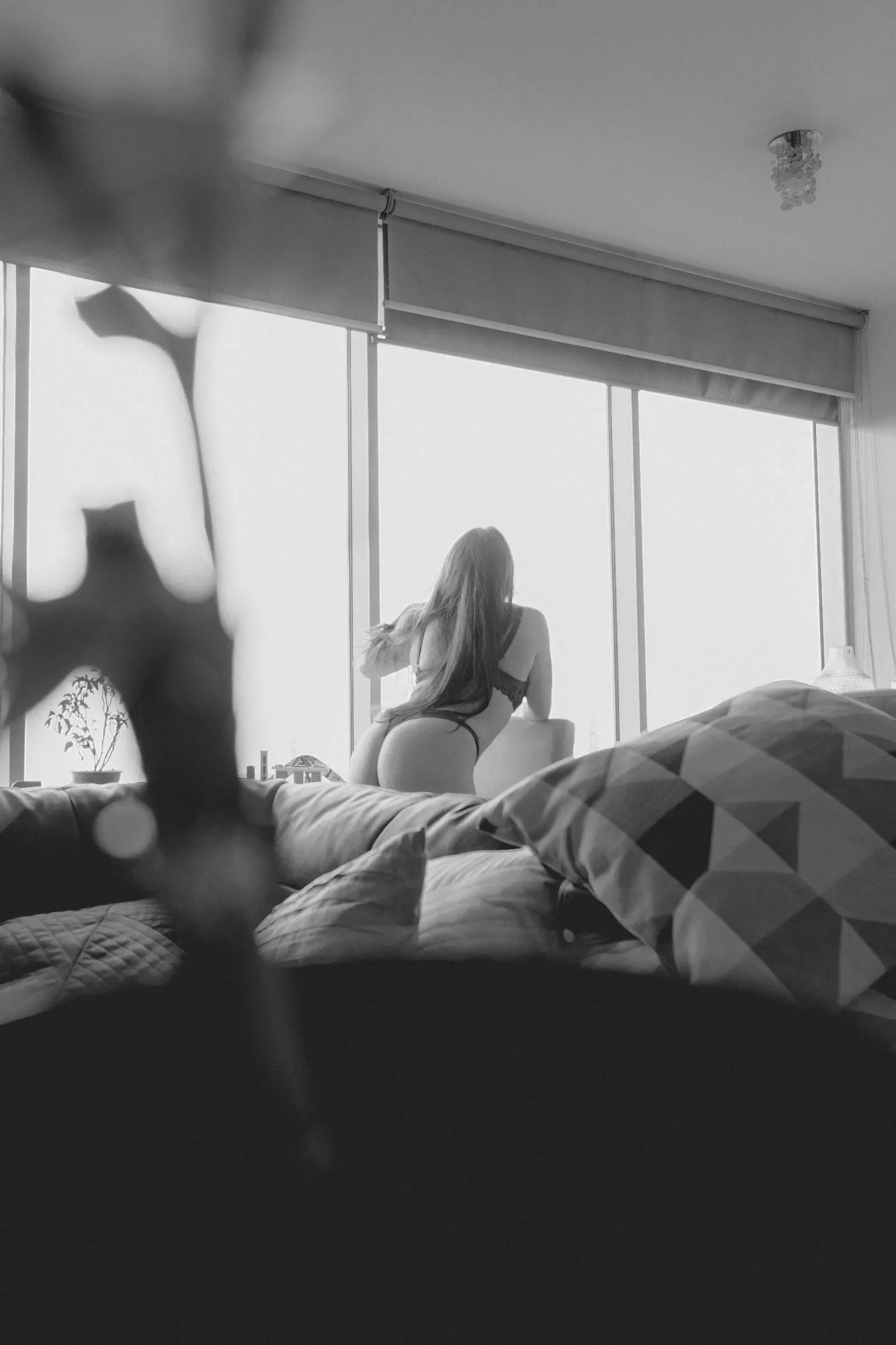 Figura femenina enmarcada por ventana con texturas en interior moderno, boudoir