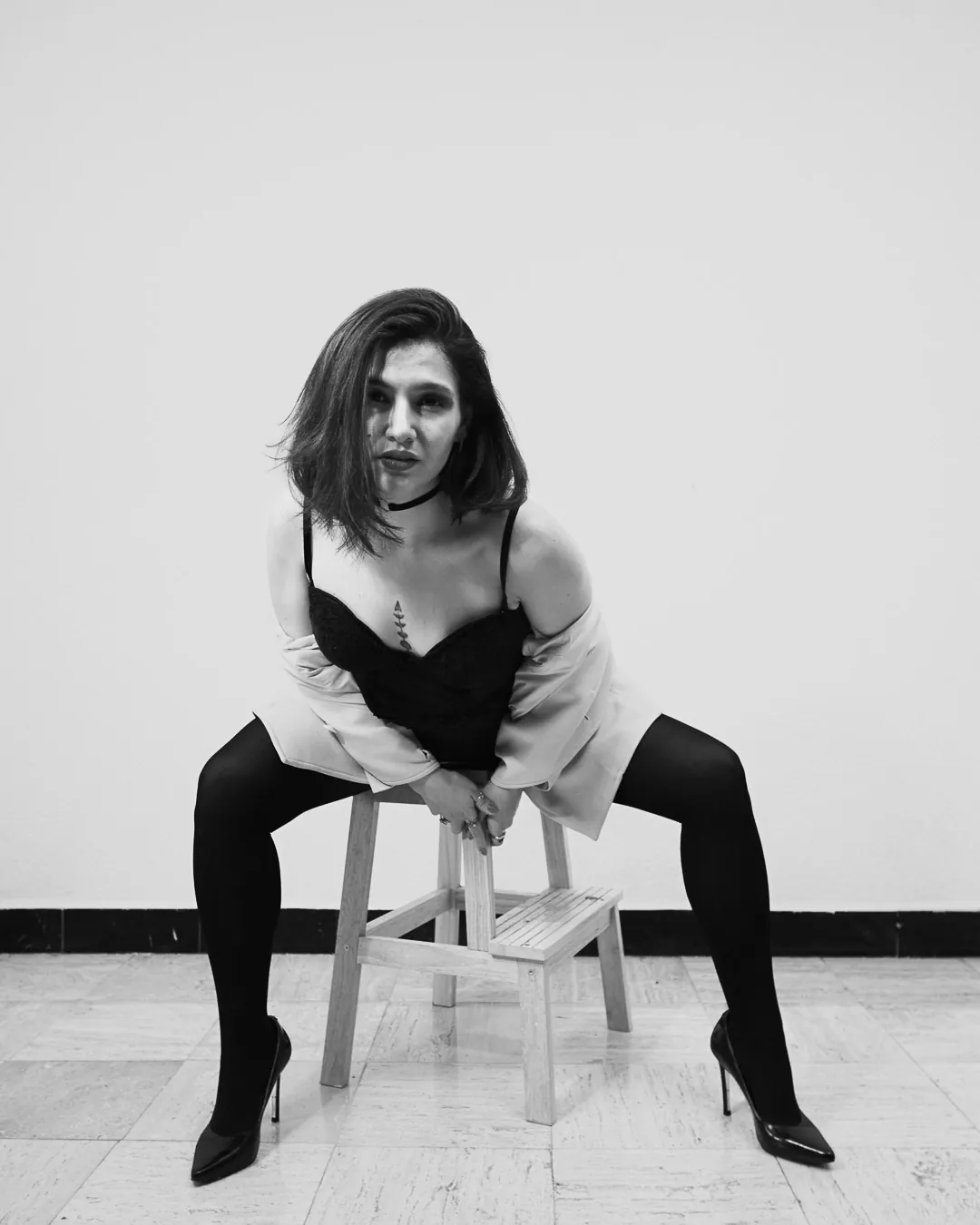 Mujer sentada de frente con saco caído sobre los hombros y corsé negro, boudoir de estudio