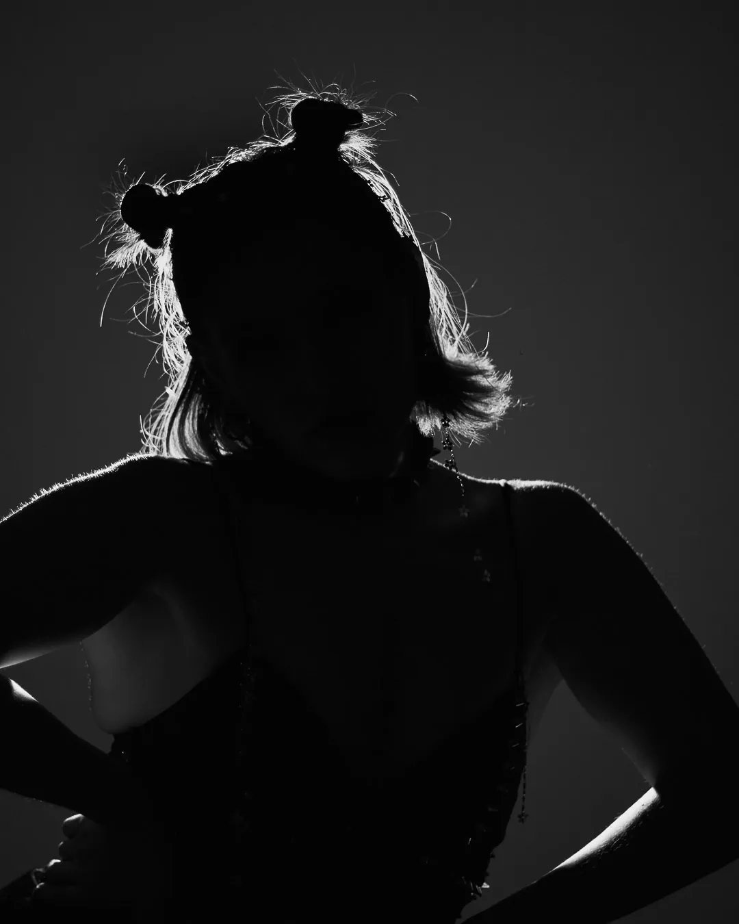 Silueta a contraluz de mujer de espaldas con chongos, boudoir de estudio en blanco y negro