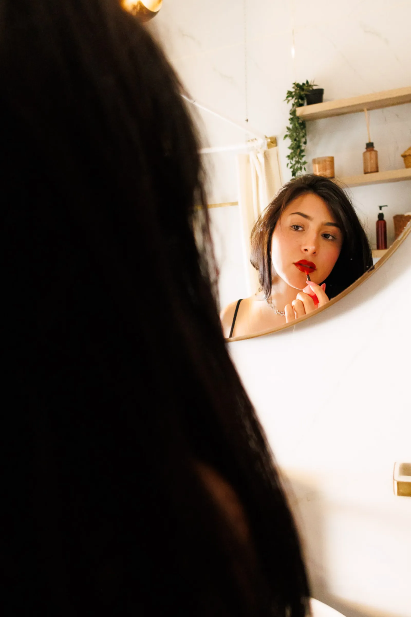 Mujer aplicándose labial rojo frente al espejo, reflejo íntimo sesión boudoir individual CDMX
