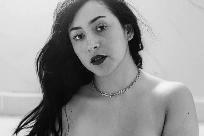 Retrato boudoir en blanco y negro de mujer con cabello largo, labios oscuros y collar de estrellas plateado, sesión individual CDMX
